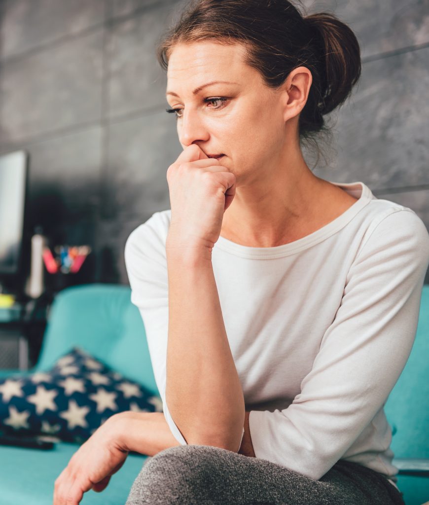 Sad woman sitting on a sofa in the living room